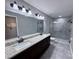 Modern bathroom with double vanity, granite countertop, and glass-enclosed shower at 5320 Sw 128Th Pl, Ocala, FL 34473