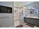 Bright bathroom showcasing a glass shower, modern vanity, wall-mounted tv, and tile flooring at 5845 Sw 43Rd Street Rd, Ocala, FL 34474