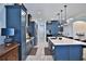 Open kitchen features blue cabinets, stainless steel appliances, an island, and decorative pendant lighting at 5845 Sw 43Rd Street Rd, Ocala, FL 34474