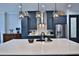 Kitchen boasts an island with white countertop, blue cabinetry, stainless appliances, and modern pendant lights at 5845 Sw 43Rd Street Rd, Ocala, FL 34474