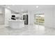 Modern white kitchen featuring stainless steel appliances, an island, and sliding glass doors to the backyard at 6240 Cherry Rd, Ocala, FL 34472