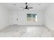 Large open room with marble-look tile floors, ceiling fan and a white door at 6240 Cherry Rd, Ocala, FL 34472