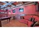 Entertain in this stylish game room featuring hardwood floors, red walls, and a comfortable curved couch at 695 Se 47Th Loop, Ocala, FL 34480