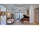 Spacious living room boasts a grand piano, tray ceilings, and scenic views of the pool at 695 Se 47Th Loop, Ocala, FL 34480
