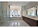 The main bath boasts double sinks, wood cabinets, a glass shower, and a soaking tub by large windows at 695 Se 47Th Loop, Ocala, FL 34480