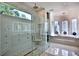 This luxurious main bathroom features a glass shower, soaking tub by large windows, and modern fixtures at 695 Se 47Th Loop, Ocala, FL 34480
