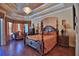 This main bedroom offers a tray ceiling, hardwood floors, a four-poster bed, and ample natural light at 695 Se 47Th Loop, Ocala, FL 34480