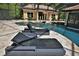Screened-in pool area with luxury lounge chairs and tropical landscaping and water feature at 695 Se 47Th Loop, Ocala, FL 34480