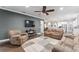 Inviting living room featuring a ceiling fan, large sectional sofa, and seamless access to the kitchen at 7839 Sw 97Th Cir, Ocala, FL 34481