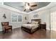 Comfortable main bedroom with tray ceiling, plantation shutters, ceiling fan, and hardwood floors at 7839 Sw 97Th Cir, Ocala, FL 34481
