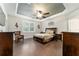 Comfortable main bedroom with tray ceiling, plantation shutters, ceiling fan, and hardwood floors at 7839 Sw 97Th Cir, Ocala, FL 34481