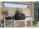 Outdoor kitchen with stainless steel grill, mini fridge, and sink, accented by stylish stone backsplash at 7839 Sw 97Th Cir, Ocala, FL 34481