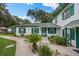 Charming exterior view of a white house with green trim, beautifully landscaped with walkways and lush greenery at 7961 Midway Drive Ter # J102, Ocala, FL 34472