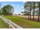 Scenic view of lush green grass, white fence, and towering trees against a blue sky at 8611 Sw 83Rd Loop, Ocala, FL 34481