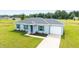 Well-maintained one-story home with a gray roof, blue shutters, green lawn, and concrete driveway at 87 Redwood Rd, Ocala, FL 34472