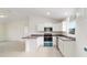 Modern kitchen features white cabinets, stainless steel appliances, and a dark countertop with an adjacent living area at 87 Redwood Rd, Ocala, FL 34472