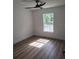Bright bedroom featuring wood-look floors, a modern ceiling fan, and a window with a view of the outdoors at 9721 Bahia Rd, Ocala, FL 34472