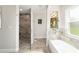 Bright bathroom with a soaking tub, glass enclosed shower with gray tiling, and a decorative plant at 9957 Sw 45Th Ave, Ocala, FL 34476
