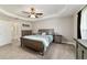 Spacious bedroom featuring a trey ceiling, a ceiling fan, neutral paint and carpet, and views to the ensuite at 9957 Sw 45Th Ave, Ocala, FL 34476