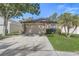 Tan home featuring a two-car garage, mature trees, and a well manicured lawn at 125 Placid Woods Ct, Sanford, FL 32773