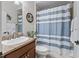 Cozy bathroom featuring a shower with blue striped curtains and a decorative palm tree wall art at 1266 James Island St, The Villages, FL 32162