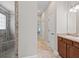 Hallway view of bathroom shower and bedroom with bed and ceiling fan in the distance at 1266 James Island St, The Villages, FL 32162