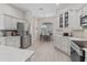 Bright, all-white kitchen with stainless steel appliances, complemented by a cozy dining area with window view at 1266 James Island St, The Villages, FL 32162