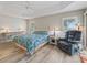 Bright bedroom features light wood floors, tray ceiling, recliner, and windows with shutters at 1266 James Island St, The Villages, FL 32162