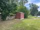 Metal outbuilding on a grassy lot with a wooden fence and storage at 145 Ne 71St Ave, Ocala, FL 34470