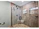 Detailed view of a shower with pebble floor, wood-look tiles, glass door, and storage shelves at 15360 Se 73Rd Avenue, Summerfield, FL 34491
