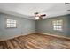 Bedroom featuring beautiful wood-look floors, natural light from two windows, and a ceiling fan at 15360 Se 73Rd Avenue, Summerfield, FL 34491