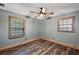 Bright bedroom with two windows, wood-look floors, ceiling fan, and light gray paint at 15360 Se 73Rd Avenue, Summerfield, FL 34491