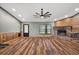 Spacious living room with a brick fireplace, wood paneling, vinyl floors, and a ceiling fan at 15360 Se 73Rd Avenue, Summerfield, FL 34491