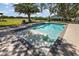 Sparkling pool features sun shelf, mosaic details, and lush landscaping at 15360 Se 73Rd Avenue, Summerfield, FL 34491