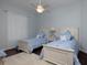 Cozy bedroom features blue decor, hardwood floors, and twin beds, creating a comfortable and inviting space at 1953 Hartford Path, The Villages, FL 32162