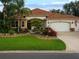 Beautiful landscaped front yard with colorful flowers, a stone walkway, and a two-car garage at 1953 Hartford Path, The Villages, FL 32162