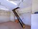 View of the pull-down ladder stairs leading to storage with fans and shelving at 1953 Hartford Path, The Villages, FL 32162