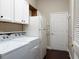 Functional laundry area with appliances, storage cabinets, and convenient access to a nearby door at 1953 Hartford Path, The Villages, FL 32162