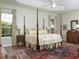 This primary bedroom features an elegant four poster bed, tray ceiling, and hardwood floors at 1953 Hartford Path, The Villages, FL 32162