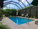 Screened-in pool area is surrounded by lush landscaping, offering a private outdoor oasis at 1953 Hartford Path, The Villages, FL 32162