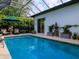 This screened-in pool has a water feature, poolside seating, and a sliding glass door for convenience at 1953 Hartford Path, The Villages, FL 32162