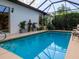 Backyard screened-in pool features clear blue water with water feature and patio seating at 1953 Hartford Path, The Villages, FL 32162