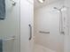 Modern white shower featuring grab bars, an adjustable shower head, and a built-in seat for added comfort and accessibility at 1953 Hartford Path, The Villages, FL 32162