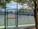 Tennis court with a chain-link fence, visible players, and posted courtesy rules for community use at 1953 Hartford Path, The Villages, FL 32162
