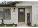 Home entryway featuring a decorative front door, exterior light fixture, and fresh landscaping at 21191 Sw Plantation St, Dunnellon, FL 34431