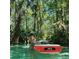 A Personal enjoys the beauty of a clear river surrounded by lush green vegetation and tall trees at 21191 Sw Plantation St, Dunnellon, FL 34431