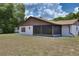 Rear view of the house featuring stucco walls, a screened-in porch, and a well-kept lawn at 3427 Se 137Th St, Summerfield, FL 34491