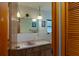 Compact bathroom exhibiting a pink sink, neutral tile, decorative lights, and wood vanity at 3427 Se 137Th St, Summerfield, FL 34491