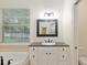 Bathroom featuring a vanity with granite countertops, framed mirror, tub, and toilet at 3883 Se 51St Ct, Ocala, FL 34480