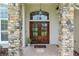 Detailed view of the stone-clad entry with double wood doors and decorative transom window at 3883 Se 51St Ct, Ocala, FL 34480